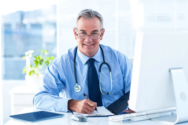 Arzt schreibt Daten am Schreibtisch im Krankenhaus — Stockfoto