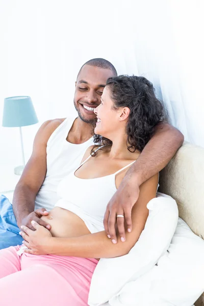 Pregnant woman with husband lying on bed — Stock Photo, Image