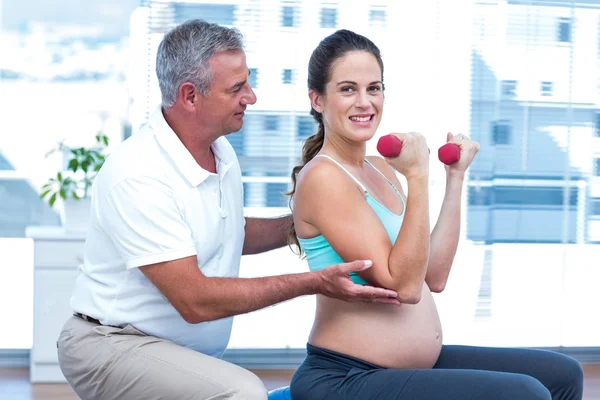 Инструктор, помогающий жизнерадостной беременной женщине — стоковое фото