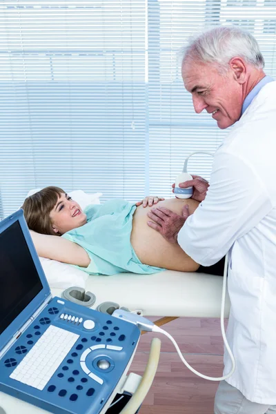 Médico segurando equipamentos na barriga da mulher — Fotografia de Stock