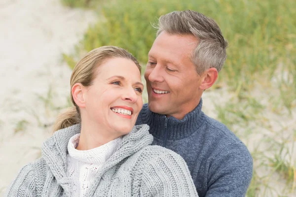 Couple souriant assis sur le sable — Photo