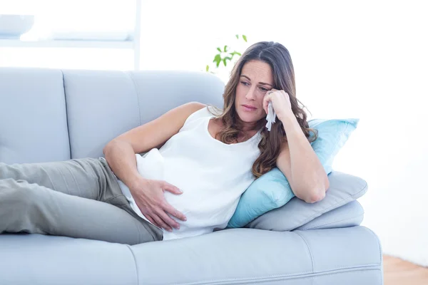 Sad pregnant woman lying on sofa — Stock Photo, Image