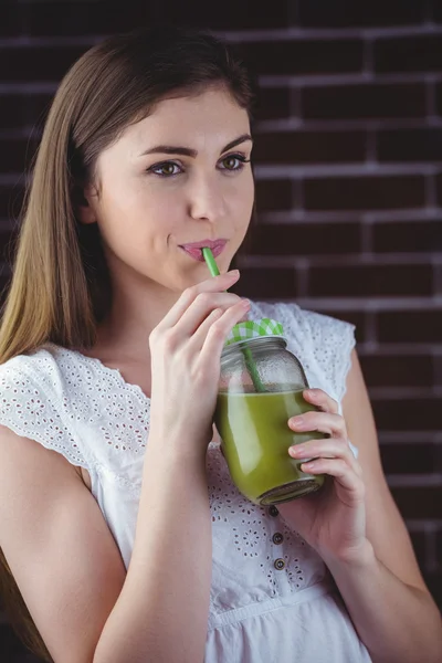 Mulher sorvendo em suco verde — Fotografia de Stock