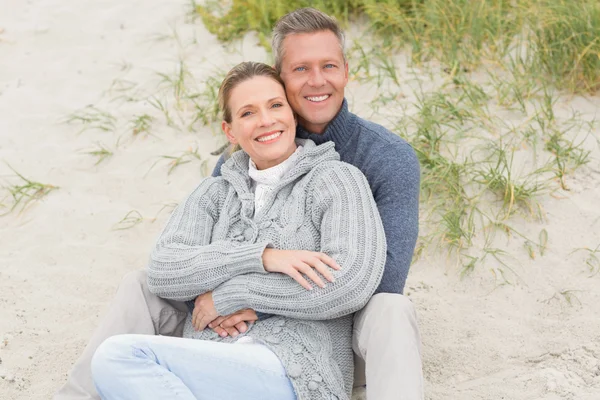 Smiling couple sitting on sand Royalty Free Stock Photos