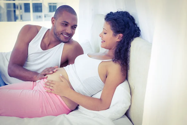 Husband lying with pregnant wife on bed — Stock Photo, Image