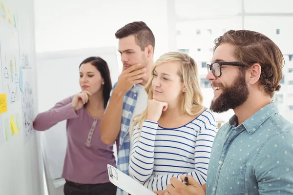 Thoughtful business people pointing at wall — Stock Photo, Image