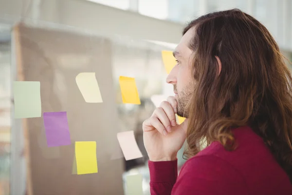 Thoughtful man looking at adhesive notes — Stock Photo, Image