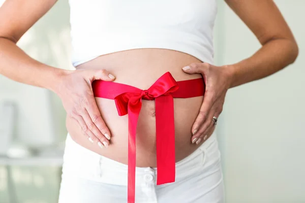 Parte central da mulher segurando barriga com fita — Fotografia de Stock