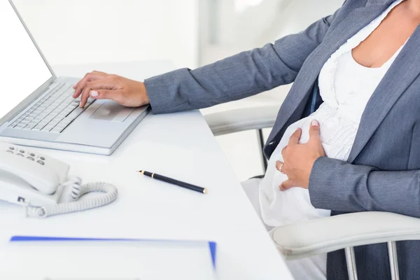 Schwangere Geschäftsfrau berührt ihren Bauch — Stockfoto