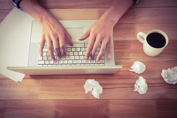 Man working on laptop by black coffee at desk in office