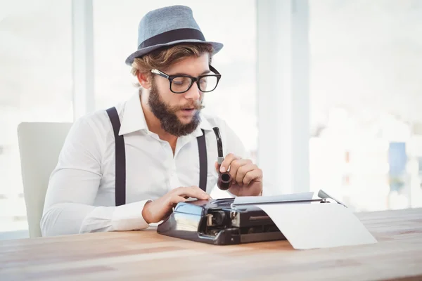 Hipster sosteniendo pipa de fumar mientras trabaja en la máquina de escribir —  Fotos de Stock