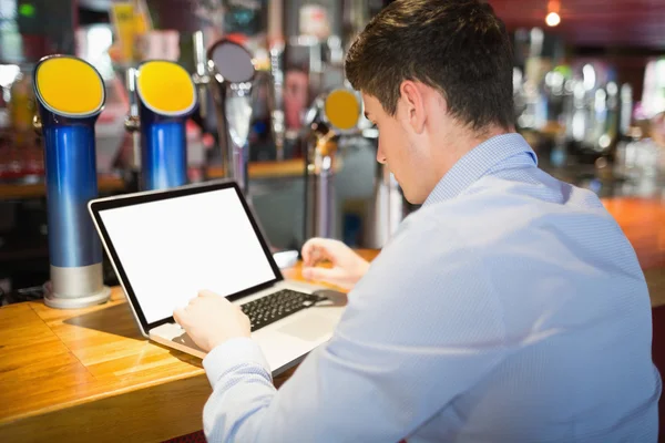 Man working on laptop at bar counter — Stock Photo, Image