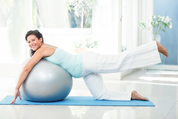 Mujer embarazada sonriente estirándose con bola de ejercicio — Foto de Stock