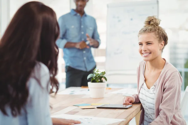 Leende kvinna diskuterar med medarbetare — Stockfoto