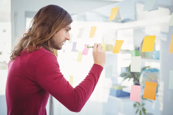 Hipster schrijven op notitie geplakt op glas — Stockfoto