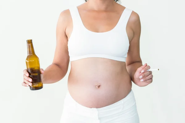 Mujer embarazada sosteniendo cigarrillo y botella de cerveza — Foto de Stock