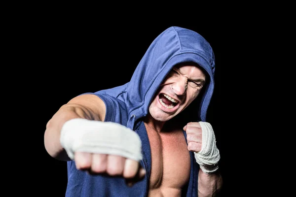 Aggressive fighter punching against black background — Stock Photo, Image