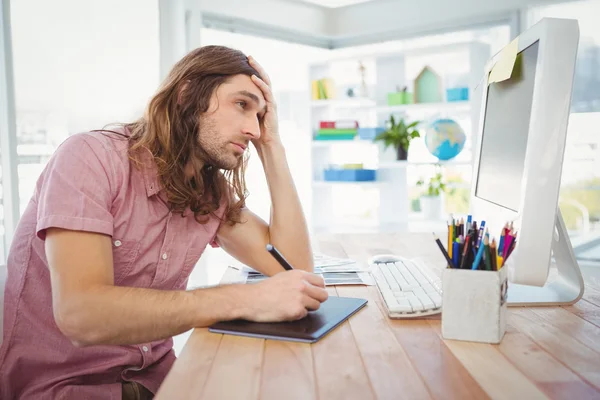 Tired hipster working on graphics tablet and computer — Stock Photo, Image