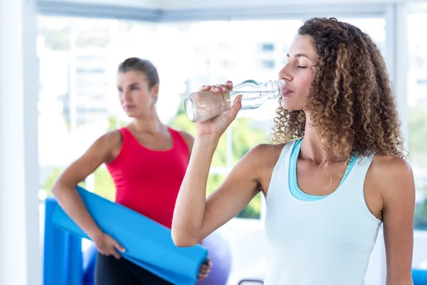 Женщина пьет воду в фитнес-студии — стоковое фото