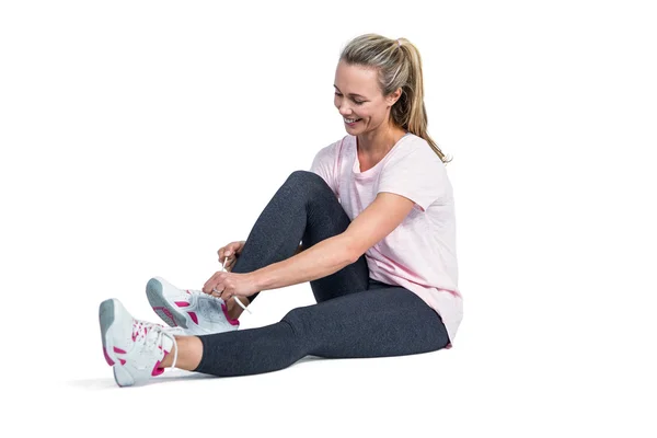 Sporty woman smiling while tying shoelace — Stock Photo, Image