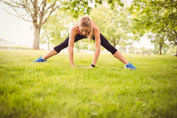 Vältränad kvinna tränar med stretching ben — Stockfoto