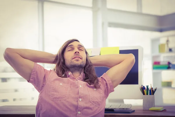 Hipster con le mani dietro la testa appoggiate alla scrivania del computer — Foto Stock