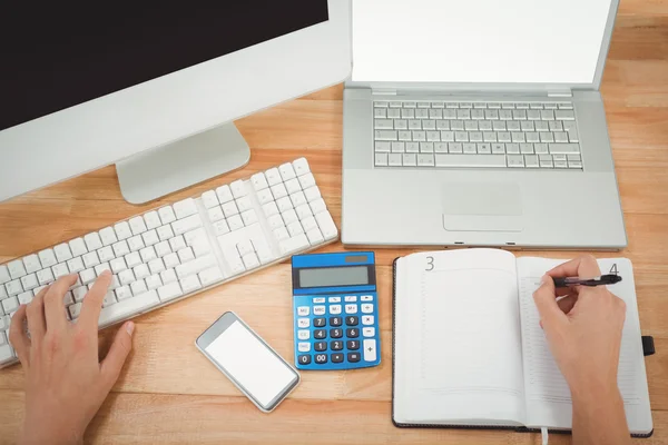 Homme d'affaires écrit sur le journal en utilisant l'ordinateur au bureau — Photo