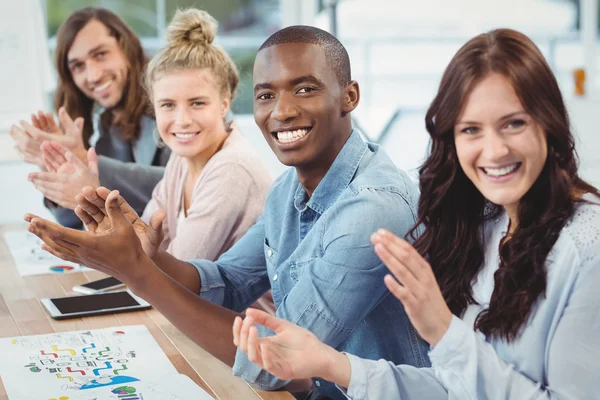 Porträt lächelnder Geschäftsleute, die am Schreibtisch klatschen — Stockfoto