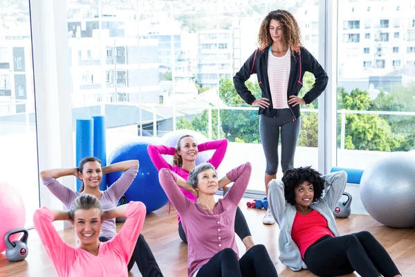 Jonge vrouwelijke trainer helpen vrouwen sit-ups — Stockfoto