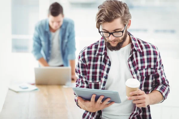 Biznesmen za pomocą cyfrowego tabletu i kubek kawy gospodarstwa — Zdjęcie stockowe