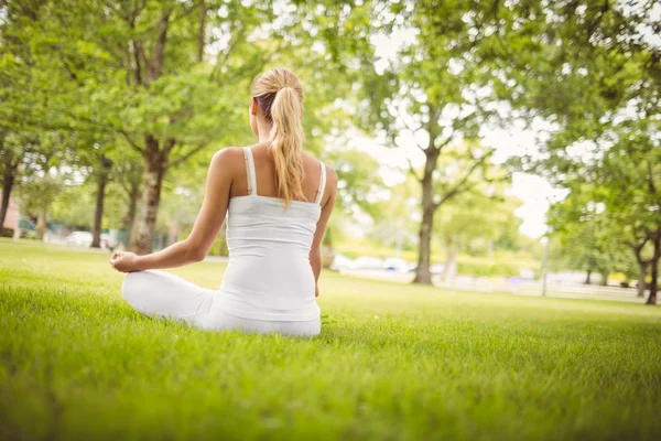 Vista trasera de la mujer meditando mientras está sentada en pose de loto — Foto de Stock