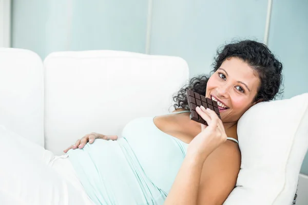 Mulher grávida feliz comer barra de chocolate — Fotografia de Stock