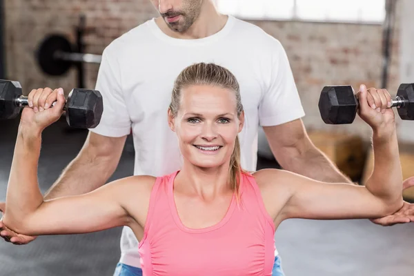 Passar kvinnan lyfta hantlar med tränare — Stockfoto