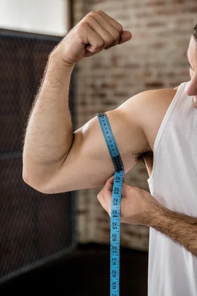 Hombre muscular midiendo bíceps —  Fotos de Stock