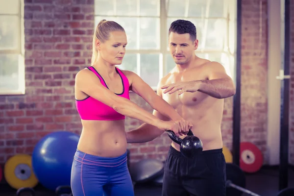 Treinador muscular atento mostrar como levantar kettlebells — Fotografia de Stock