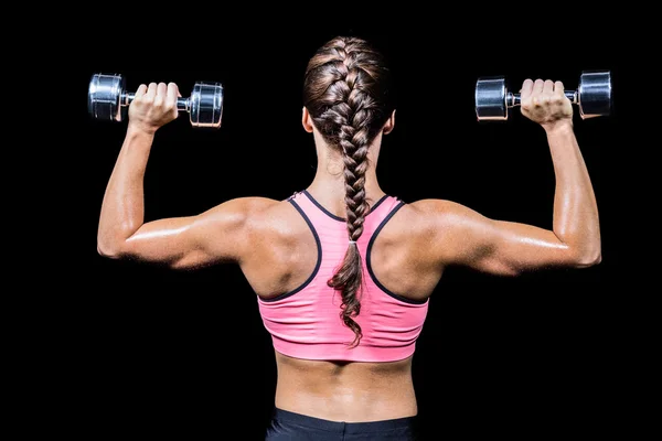 Rear view of braided hair woman exercising dumbbells — Stock Photo, Image
