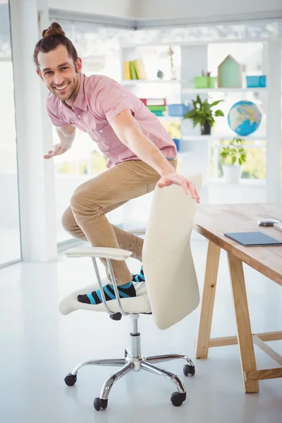 Feliz hombre de negocios de pie en la silla en la oficina — Foto de Stock