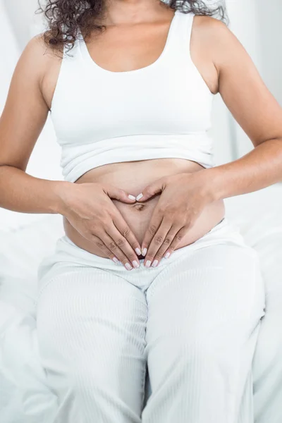 Mujer embarazada haciendo signo de corazón en el vientre —  Fotos de Stock