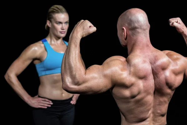 Skallig muskulös man flexar muskler framför tränare — Stockfoto