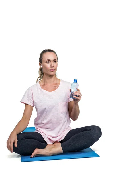 Doordachte sportieve vrouw met fles rusten op mat — Stockfoto