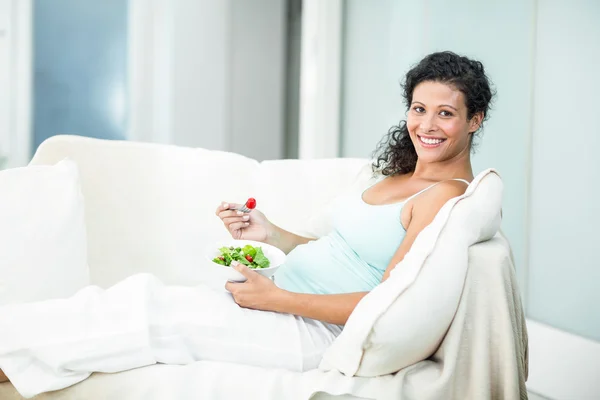 Portrait of happy woman with salad on sofa — Stock Photo, Image