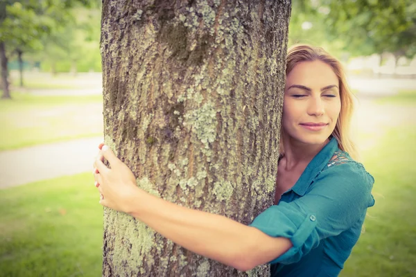 Smiling woman with eyes closed while hugging tree — Stock Photo, Image