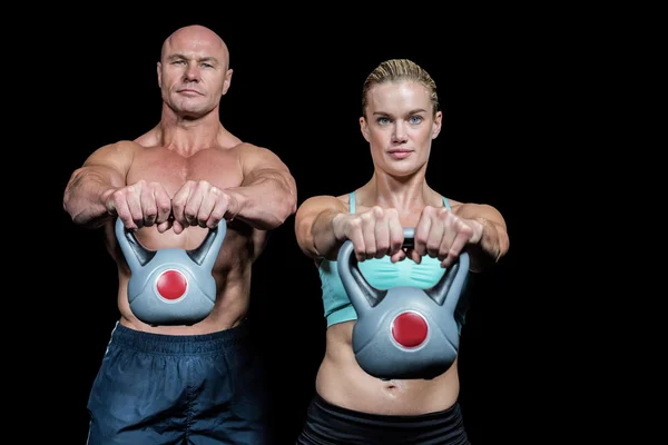 Retrato de homem muscular e mulher levantando kettlebells — Fotografia de Stock