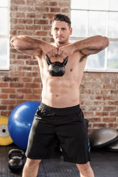 Kaslı adam bir kettlebell kaldırma — Stok fotoğraf