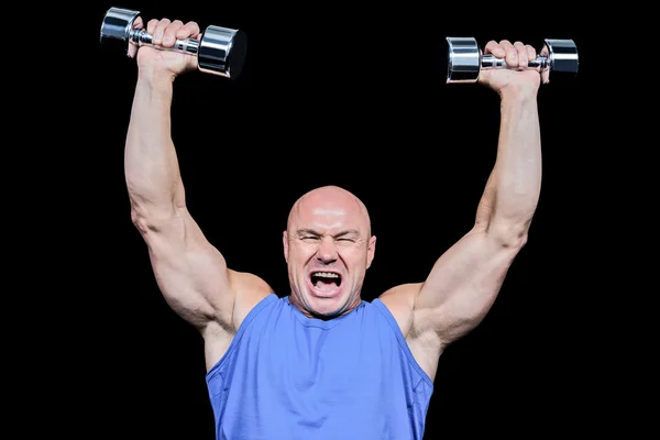 Muscular man with arms raised lifting dumbbells — Stock Photo, Image