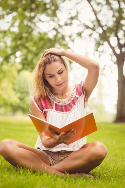 Повна довжина жінки з рукою в волоссі під час читання книги — стокове фото