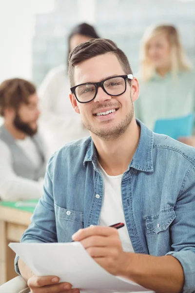 Portrait of smiling man holding paper and pen — Stock Photo, Image