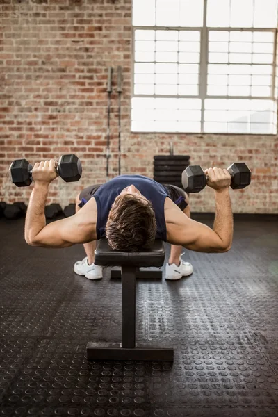 Man doing exercise with dumbbells while lying on bench — Stock Photo, Image