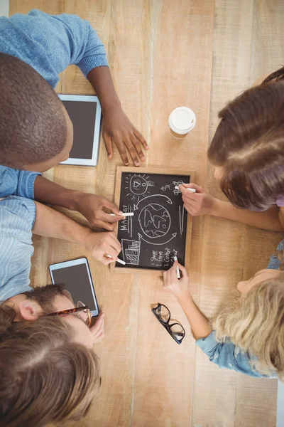 Close-up of people writing business terms on slate — Stock Photo, Image