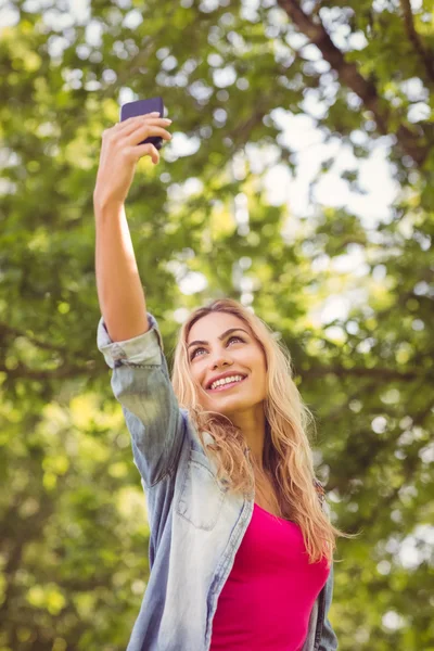 Low angle view of smiling woman taking selfie — Stock Photo, Image